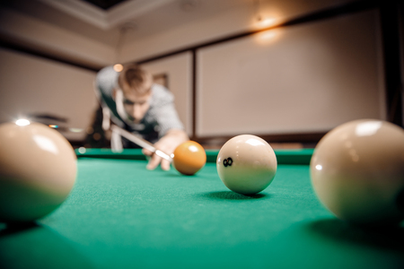 Russian billiards, man plays and beats cue on white ball.の写真素材
