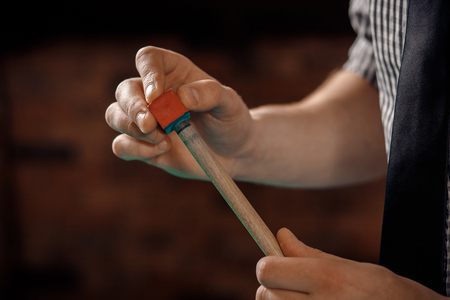 Man player sharpens cue in billiards on green table with chalk.の写真素材