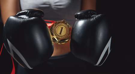 Boxing gloves hold gold medal first place in hands of female winner fighter.の写真素材