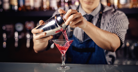 Barman prepares cocktail in shaker with alcohol and ice. Dark background Bartender.の写真素材
