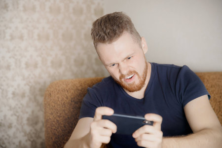 Man plays mobile phone, holds it in his hands, aggressive face.