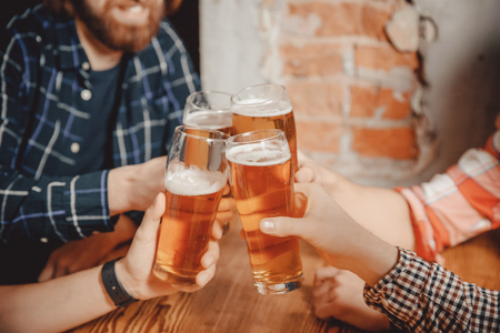 People, young guys in pub, beer restaurant, happy friends. Concept meeting, weekend, clink of glasses at bar loft style with brick wallの写真素材