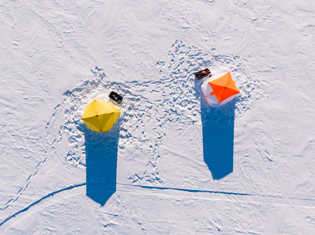 Tent for winter ice fishing, top aerial view, fisherman holding rod in hole lake.の写真素材