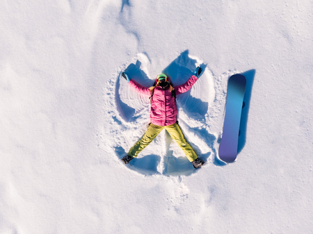 Snow angel snowboarder doing winter in bright suit. Aerial top view.の写真素材