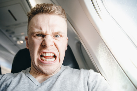 Man is angry in plane before departure. Concept aircraft delay.の写真素材