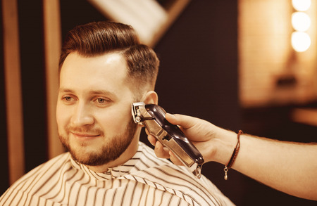 Hipster with fashionable haircut, beard trim temples barbershop electric razorの写真素材