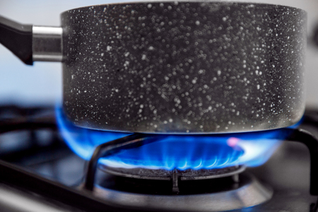 Gas stove with an open blue flame, cook on it dish in ladle.の写真素材