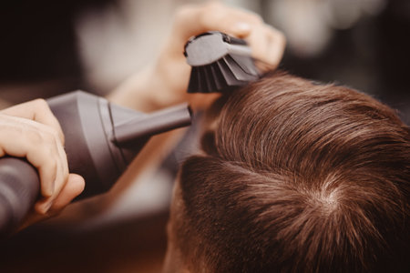 Master Barber hairstyle and styling with dryer hair to guy. Concept Barbershop. Soft focus.