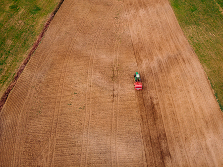 Tractor cultivate plows field of land for sowing. Concept farm. Top view aerial photo.の写真素材