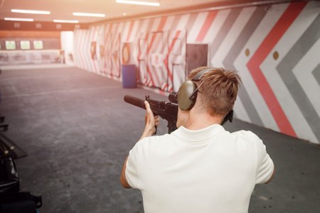 Man shoots pistol in noise protection headphones. Shooting range gun.
