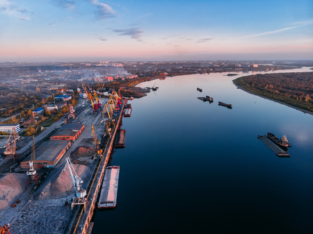 Port river cranes loading ships on barges delivery, sunset. Aerial droneの写真素材