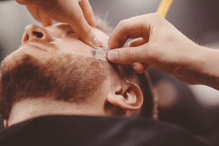 Closeup of razor blade cutting man beard Barbershop.の写真素材