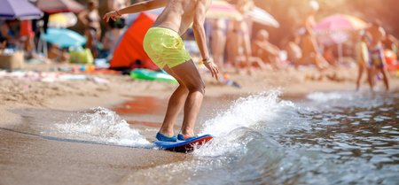 Man glides on surf waves near shore, sandy beach sunset summer.