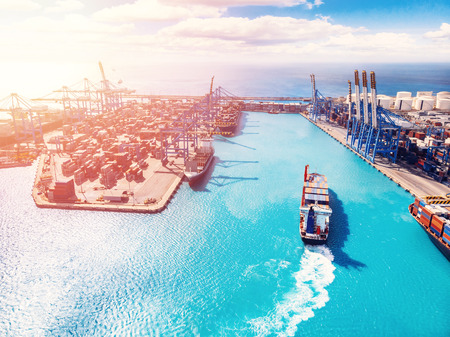 Cargo port business, logistics center. Ship is loading containers with crane. Aerial view.