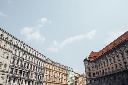 Old European street, solid building, houses, lot of Windows with decorative small balconies, red roof tiles, blue sky.の写真素材