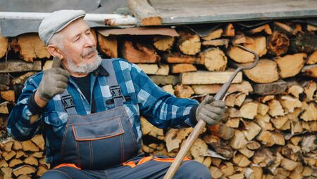 Senior smiling man is sharpening tool for cultivating farm soil. Agriculture conceptの写真素材