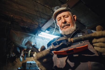 Senior elderly male turner handles metal on machine. Concept pension worker industrial, workplaceの写真素材