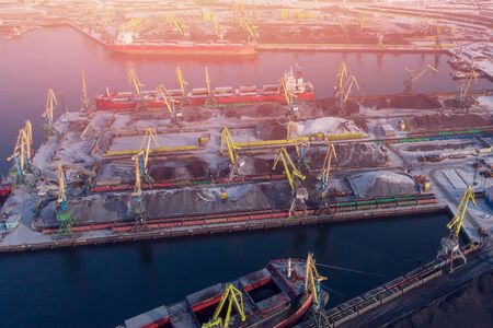 Loading coal mining in port on cargo tanker ship with crane bucket of train. Aerial top viewの写真素材