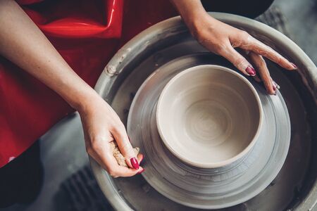 Hands of woman make clay dishes on potter wheel, Top view. Concept eleganceの写真素材