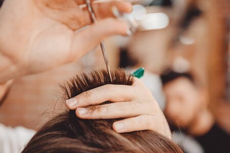 Close-up master hairdresser does hairstyle with scissors and comb. Concept Barbershopの写真素材