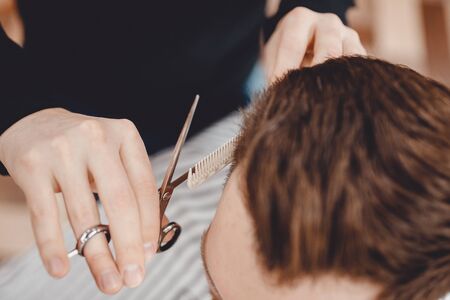 Barbershop, man barber in men hairdresser does hair with scissorsの写真素材