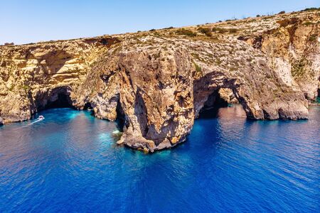 Blue Grotto in Malta. Pleasure boat with tourists runs. Natural arch window in the rock. Aerial top view.の写真素材