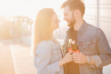 Moscow, Russia - June 27, 2019: happy couple hugging smiles and holds Coca Cola glass bottle soda in hand, sunsetのeditorial素材