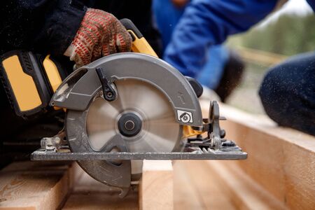 Builder uses portable circular saw tool to cut wood.の写真素材