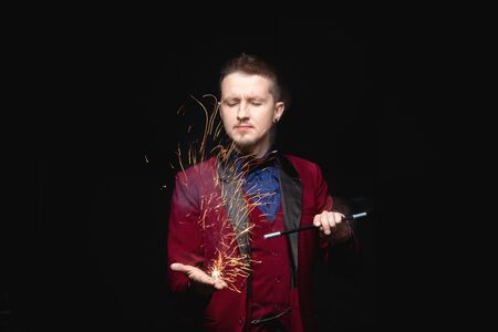 Magician shows focus fire with magic wand and sparks in his handsの写真素材