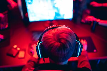 Blurred background professional gamer playing tournaments online games computer with headphones, red and blueの写真素材