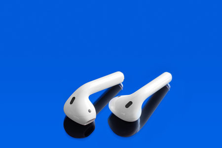 White headphones wireless earphones, copy space blue background.