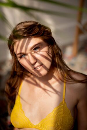 Yellow underwear. Beautiful young woman with clean skin sits on chair, concept handmade work making bra and pantiesの写真素材
