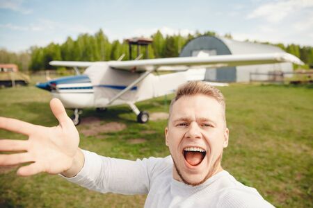 Pilot man taking selfie photo on background plane, smiling happilyの写真素材