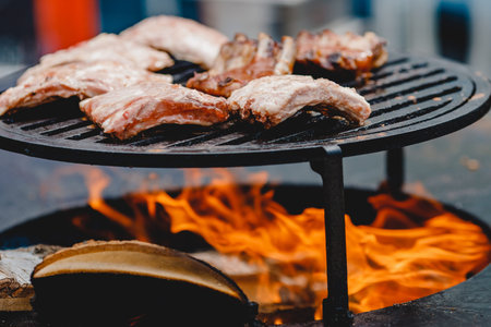 Pork ribs and steak cooked on grill, open fire street food festival.