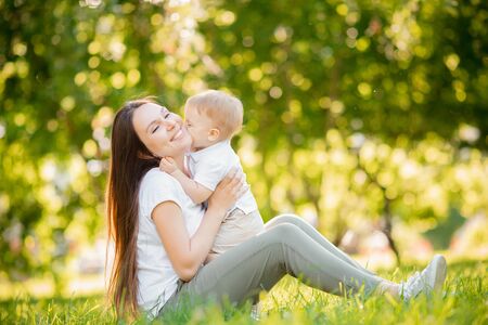 Happy family, little boy kisses his mother for walk in summer park. Childhood conceptの写真素材