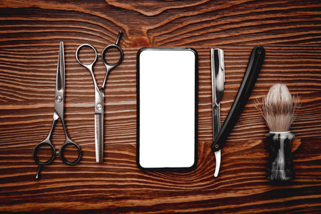 Barber shop tools with phone screen on wooden background, copy space flat lay