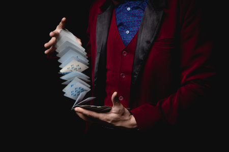 Magician shows trick with playing cards, dark background.