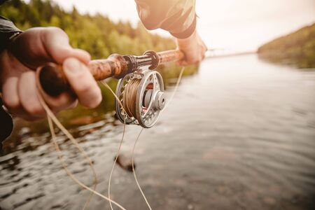 Fisherman using rod fly fishing in mountain river.の写真素材