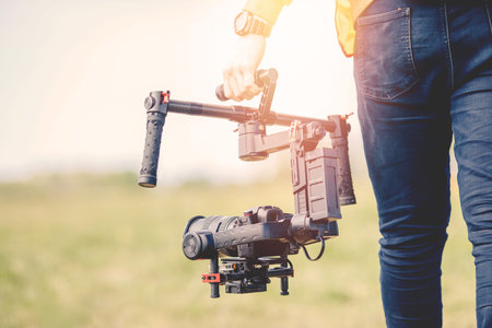 Videographer holds electronic stabilizer steadicam gimbal for DSLR camera