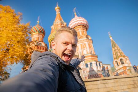 Male tourist makes selfie photo on background Saint Basil Cathedral Red Square in Moscow, Russia autumn. Travel conceptの写真素材