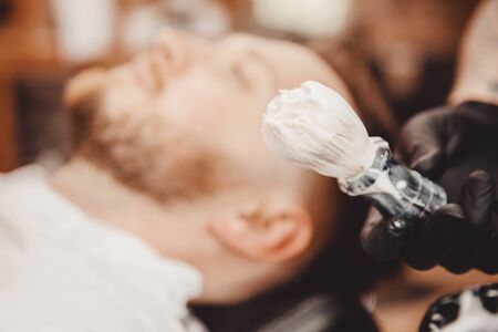 Brush for shaving beard along with bowl, blurred background of hair salon for men, barber shop.の写真素材