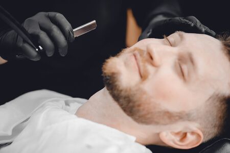 Barbershop. Hairdressers barber hair and beard with razor in salonの写真素材