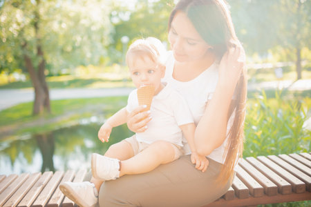 Mom shares ice cream with her baby son, happy family smiles and laughs. Sunny summer day
