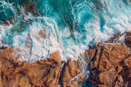 Coast of desert island with blue turquoise water beats on rocky reef. Aerial top viewの写真素材