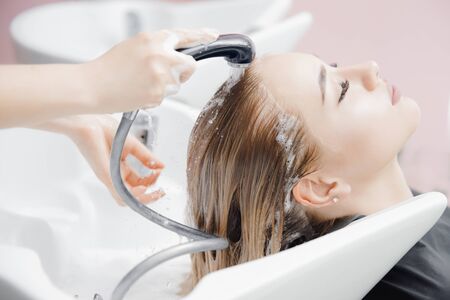 Washing hair of beautiful blonde girl in beauty salon, coloring.の写真素材