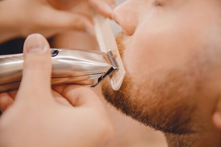 Close-up of barber shaving beard to man in barbershop.の写真素材