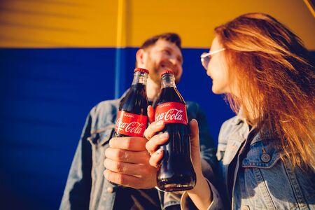 Moscow, Russia - June 27, 2019: Man and girl couple in love holding drink Coca Cola glass bottle in hands, sunsetのeditorial素材