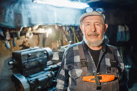 Senior elderly male turner mechanic working on machine tool for metalの写真素材