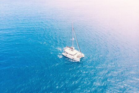 Pleasure white yacht with sail stands on coral reef in blue transparent turquoise water. Concept travel. Aerial top view.の写真素材
