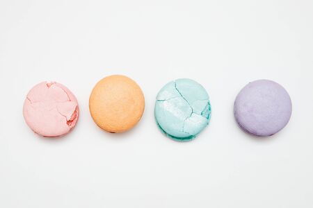 Colorful turquoise, pink, orange, purple cake French macaron or macaroon cracked on white backgroundの写真素材